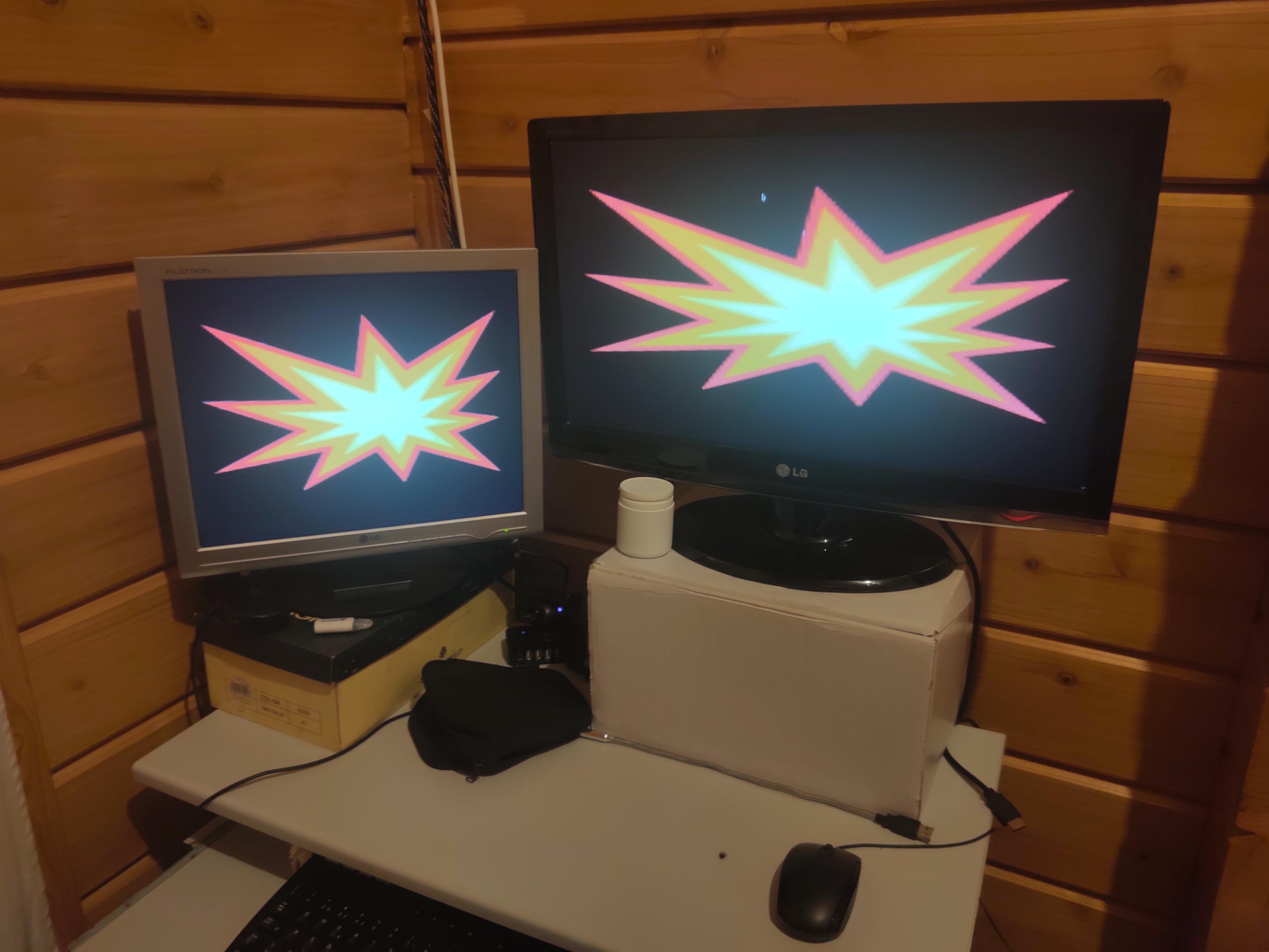 Two computer monitors, both showing an explosion image stretched across their respective screens