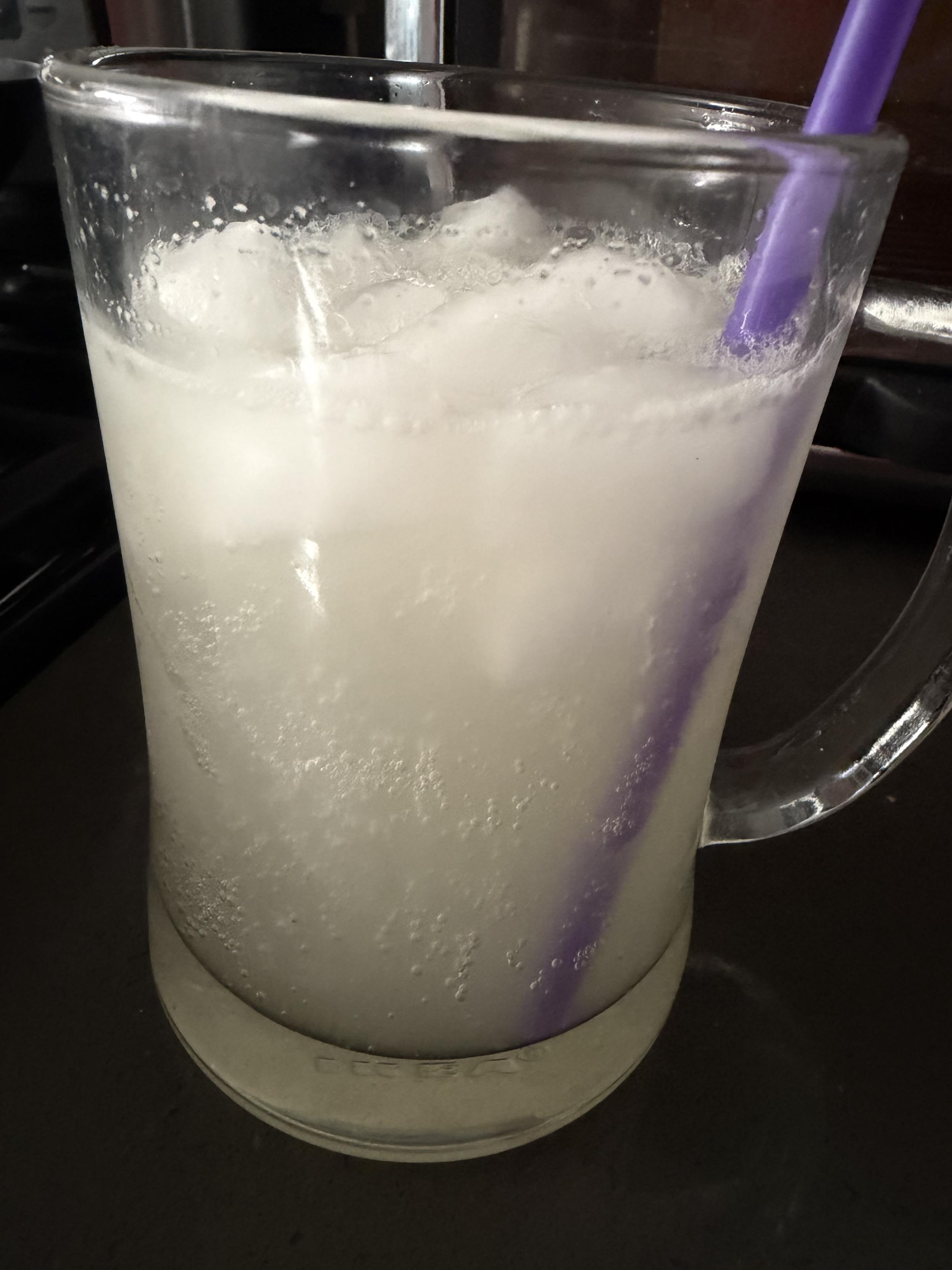 a glass of mint ginger beer with ice and a purple straw