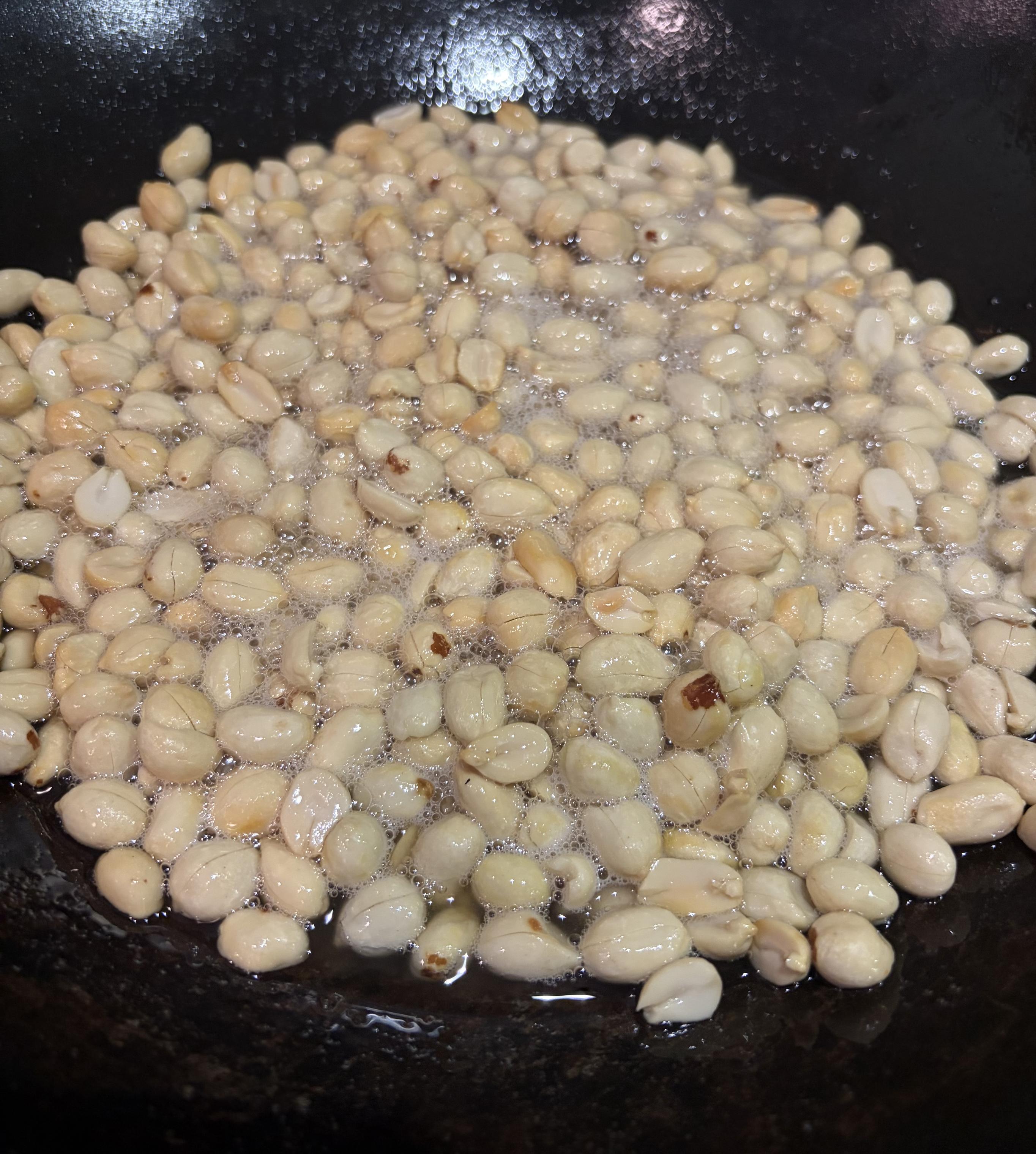 a bunch of peanuts frying in a carbon steel wok
