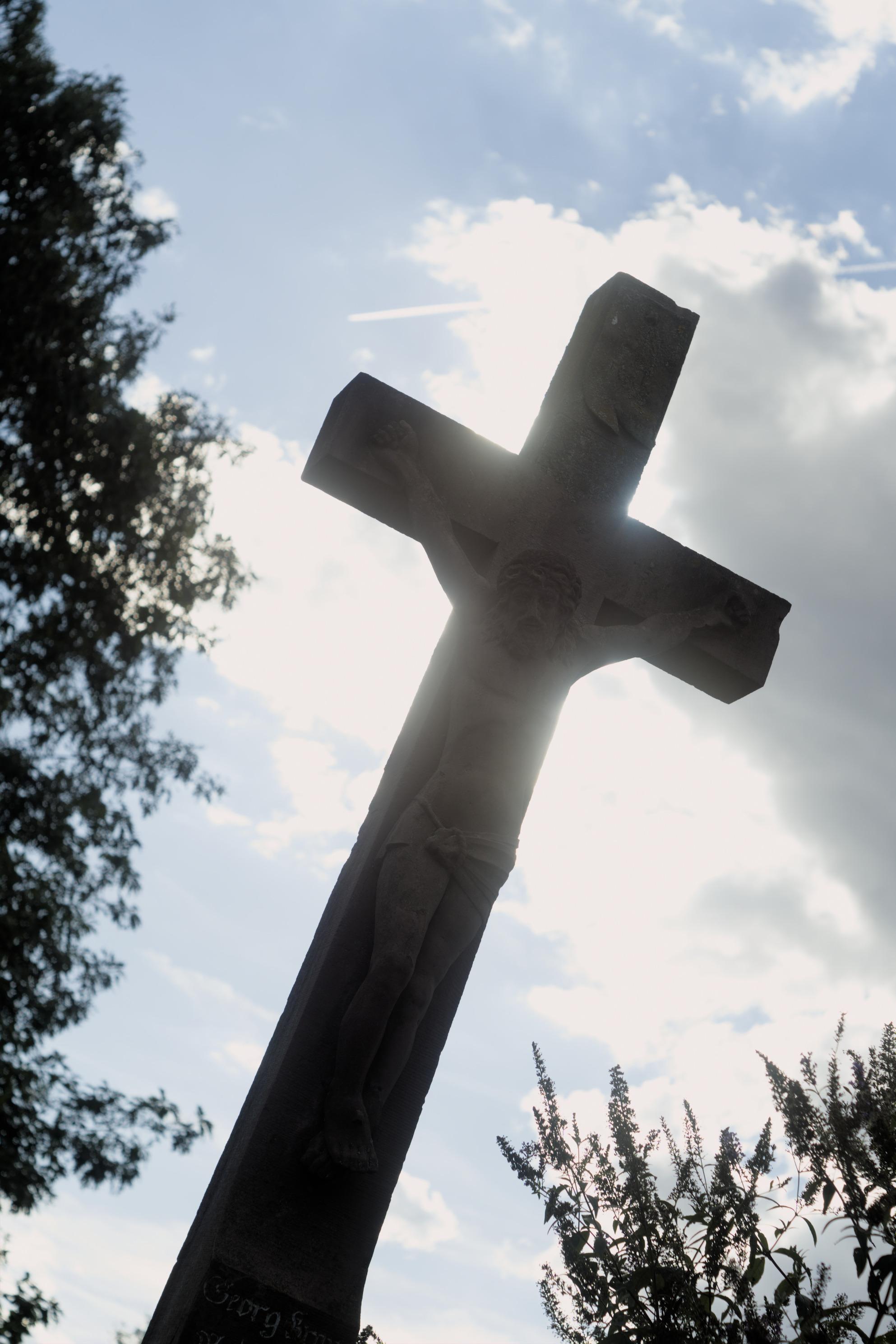 Radiant Jesus or something crucified on a cross with the sun shining on him